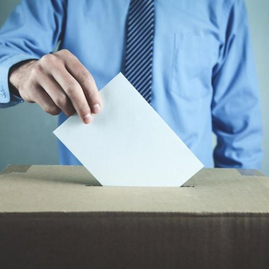 Billede af en mand der lægger en stemmeseddel i en stemmeurne